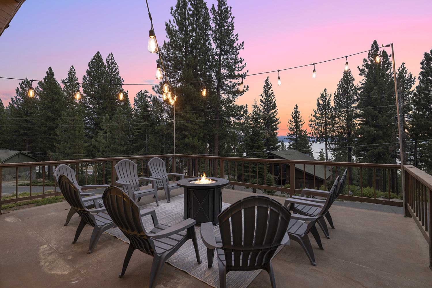 Adirondack chairs around the fire pit on the Kinpine House deck on a clear evening, string lights overhead